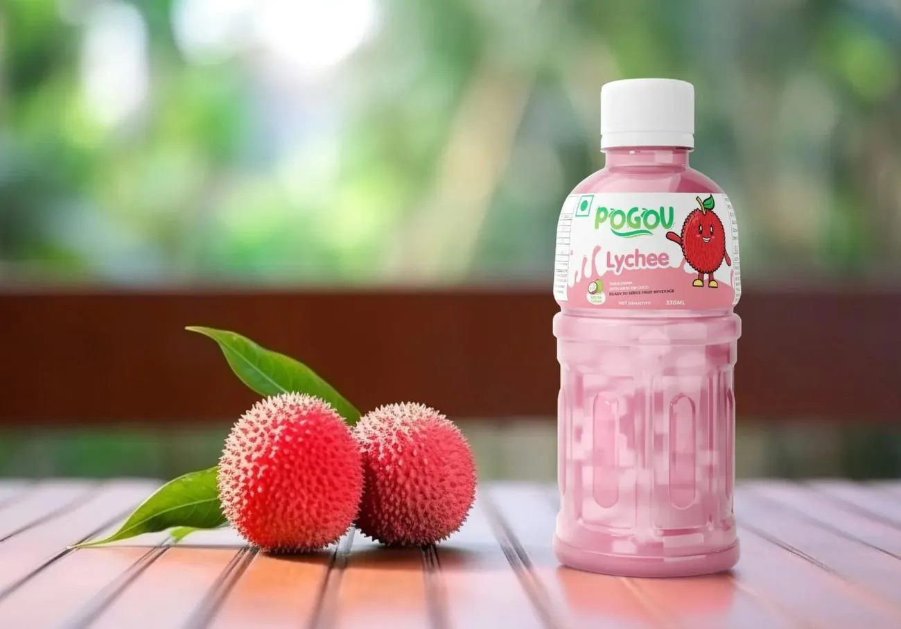 A bottle of Pogou Lychee juice beside two lychees